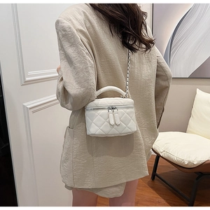 Detailed back view of model wearing white quilted crossbody bag with gold chain strap