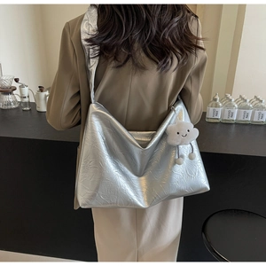 Detail of silver tote bag with metallic crinkle texture and white cloud plush charm
