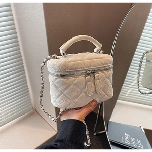 Close-up of white quilted leather vanity bag with silver chain strap and top handle