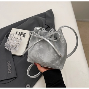 Détail du sac seau métallisé argenté avec nœud à cordon et finition texturée rétro