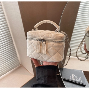 Close-up of white quilted leather vanity case with silver chain strap and top handle