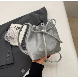 Détail du sac seau argenté à texture nacrée avec un élégant cordon à nœud