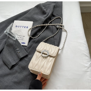 Dettaglio della borsa beige trapuntata con fibbia di perle su una giacca raffinata