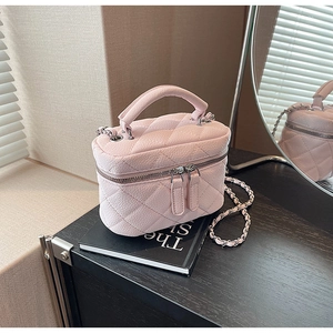 Detailed close-up of pink quilted mini bag with silver chain strap and dual zippers