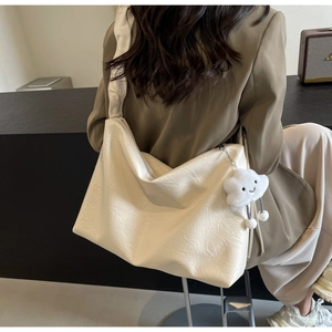 Detail of cream tote bag with pleated texture and cloud plush charm on shoulder