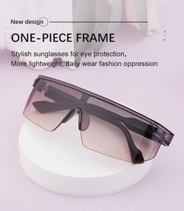 Vue détaillée de lunettes de soleil monobloc noires avec verres dégradés sur socle blanc
