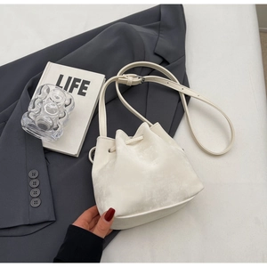 Détail du sac seau blanc cassé à cordon avec texture mate et bandoulière réglable