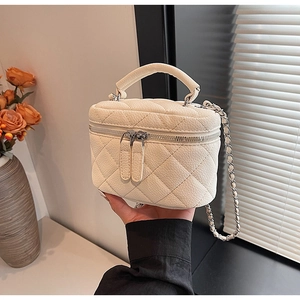Detail of a cream quilted mini bag with silver chain strap and lychee texture