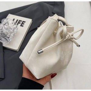 Détail du sac seau à cordon blanc cassé avec texture cuir et embouts métalliques argentés