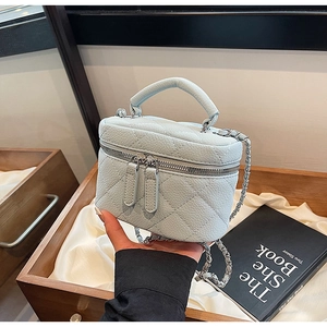 Close-up of light blue quilted mini bag with silver chain strap and lychee leather texture