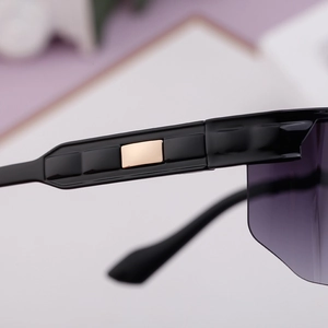 Gros plan de la branche noire avec incrustation dorée sur lunettes de soleil de sport sans bord