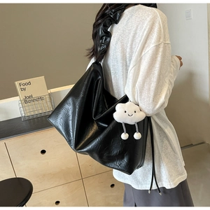 Detail of black glossy crinkled leather hobo bag with a white plush cloud charm