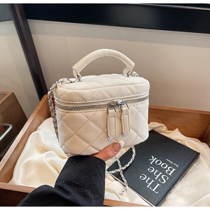 Close-up of white quilted mini chain bag with silver zipper and top handle detail