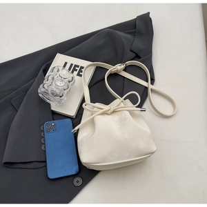 Détail du sac seau blanc crème avec nœud de serrage et texture cuir de litchi