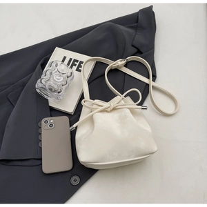 Sac seau chic couleur crème avec cordon de serrage et nœud sur un fond lifestyle élégant