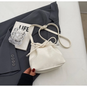Vue de dessus du sac seau blanc à cordon avec nœud en cuir sur un fond minimaliste