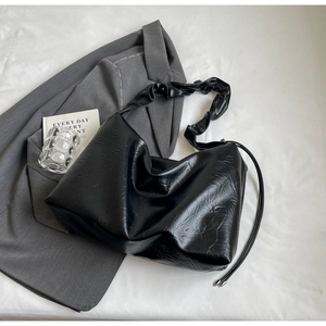 Detail of black faux leather tote bag with crinkled texture and ruched shoulder strap