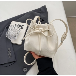 Détail d'un sac seau blanc cassé avec nœud élégant et boucle en métal argenté
