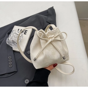 Gros plan du sac seau crème avec nœud décoratif sur une veste de costume grise