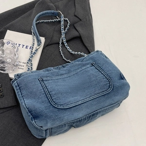 Blue denim shoulder bag with silver chain strap placed on a stylish grey blazer