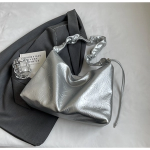 Detail of silver textured leather tote bag with pleated cloud strap on grey blazer