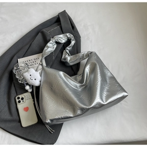 Close-up of silver textured hobo bag with a white fluffy cloud charm on a grey blazer