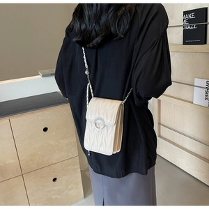 Dettaglio della borsa trapuntata avorio con elegante fibbia di perle e tracolla in pelle