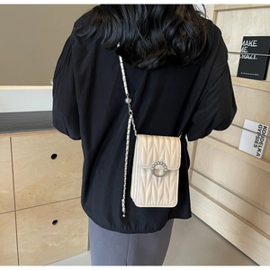 Dettaglio della borsa a tracolla trapuntata beige con fibbia di perle su legno