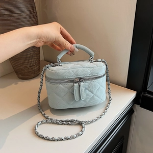 Light blue quilted mini chain bag with dual zippers and elegant top handle for women