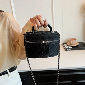 Chic black quilted crossbody bag with silver chain strap shown in an elegant interior setting