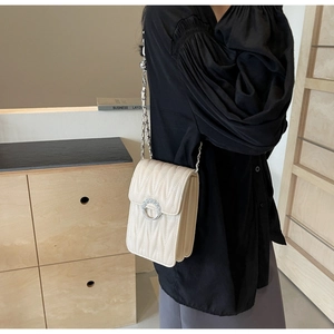 Dettaglio della borsa a tracolla trapuntata beige con fibbia di perle e catena d'argento