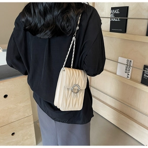 Dettaglio mini borsa trapuntata crema con fibbia di perle e tracolla a catena intrecciata
