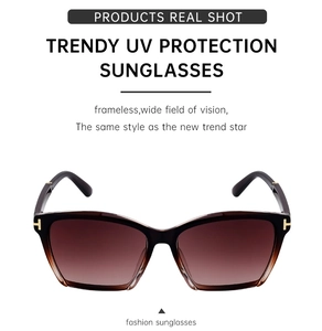 Detailed view of the gold T-logo and brown gradient lenses on polarized cat-eye sunglasses
