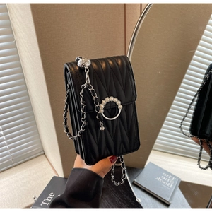 Dettaglio mini borsa trapuntata nera con fibbia di perle e tracolla a catena