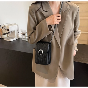 Modella che indossa una borsa trapuntata nera con fibbia a perla in un caffè moderno