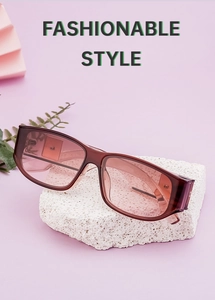 Detail view of rectangular sunglasses with brown frames and pink lenses on stone
