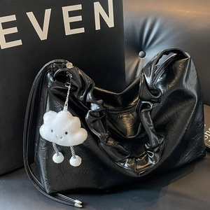 Large black crinkled patent leather tote bag with ruffle trim and cloud plush charm