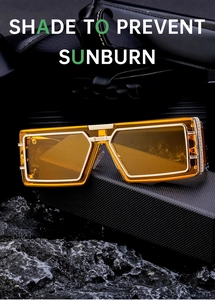 Detail of square sunglasses with orange lenses and engraved gold frames on dark rock