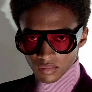Detail of oversized pilot sunglasses featuring red lenses and classic metallic T-hinge