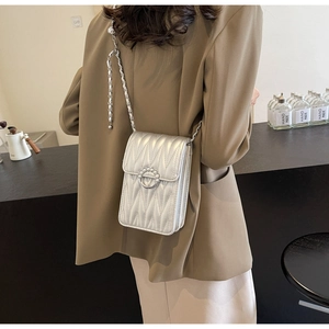 Dettaglio della borsa a catena trapuntata argento con fibbia a perla indossata al caffè