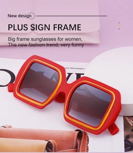Détail de lunettes de soleil carrées oversize avec monture rouge et jaune sur magazine