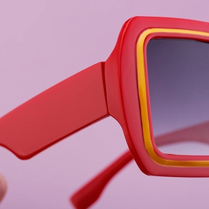 Gros plan sur des lunettes de soleil carrées avec monture bicolore rouge et jaune et verres