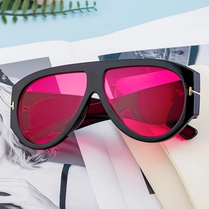 Chic oversized aviator sunglasses with black frames and magenta lenses on a magazine