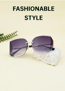 Detail view of purple gradient rimless sunglasses on a natural stone with green plants