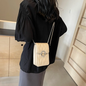 Elegante borsa a tracolla beige trapuntata con catena indossata da una modella di classe