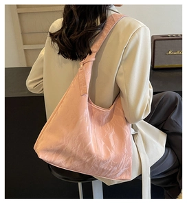Detailed view of pink hobo bag with wrinkled leather texture and wide shoulder strap