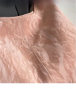 Macro detail of high-gloss pink pleated fabric texture for lightweight shoulder bag