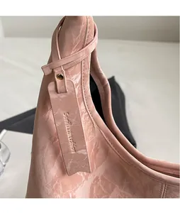 Detailed macro view of light pink tote bag featuring marble textured leather and gold studs