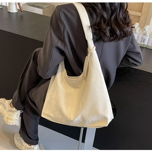 Minimalist cream white hobo shoulder bag with a wide strap shown in a cafe setting