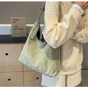 Detail of light green tote bag with unique crinkled texture and fashion brand tag